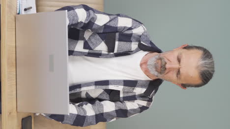 Vertical-video-of-Old-man-looking-at-laptop-applauding.